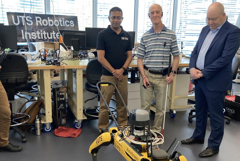 Three men look at a robot guide dog at the UTS Robotics Institute.