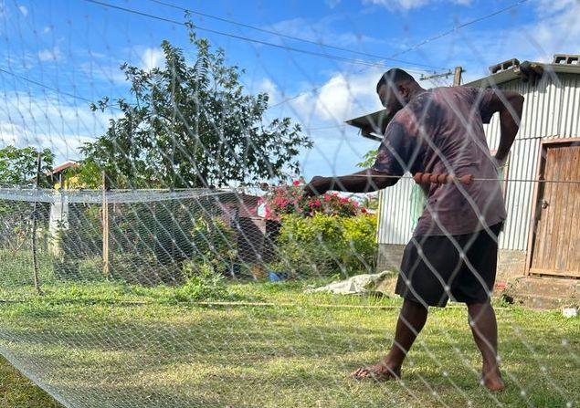 A Fijian man is fixing a fishing net