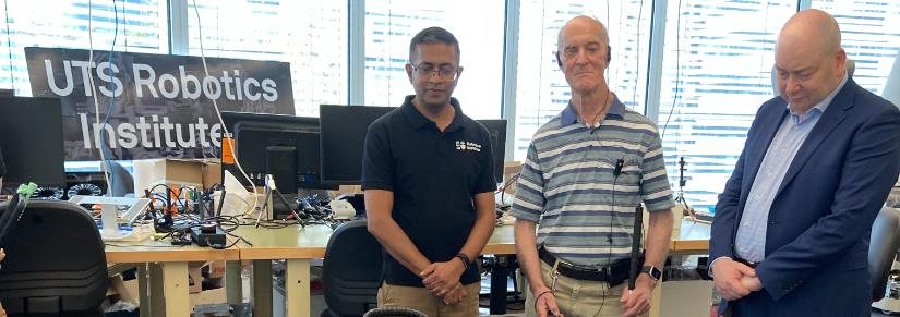 Three men look at a robot guide dog at the UTS Robotics Institute.