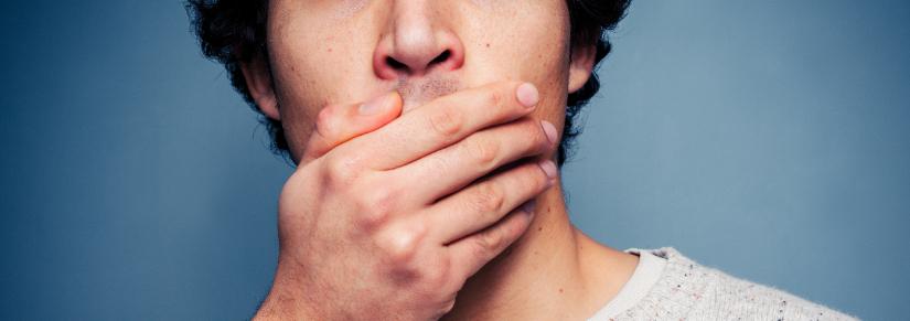 Shocked young man with his hand on his mouth.