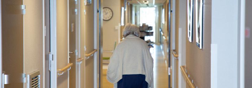 Elderly woman walking down hallway in retirement home. Adobe Stock