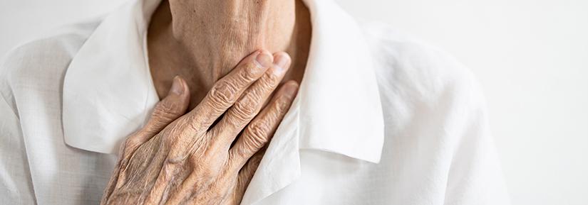 Elderly person with their hand delicately touching their throat