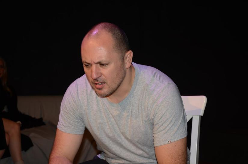 Llewellyn Spink in grey shirt sitting on chair