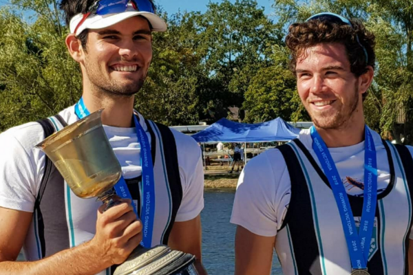 two people standing beside each other smiling, one of them holds a trophy