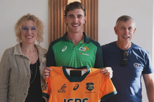 3 people standing together and smiling while holding a sporting jersey