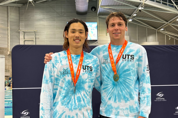two people standing beside each other and smiling with medals around their necks