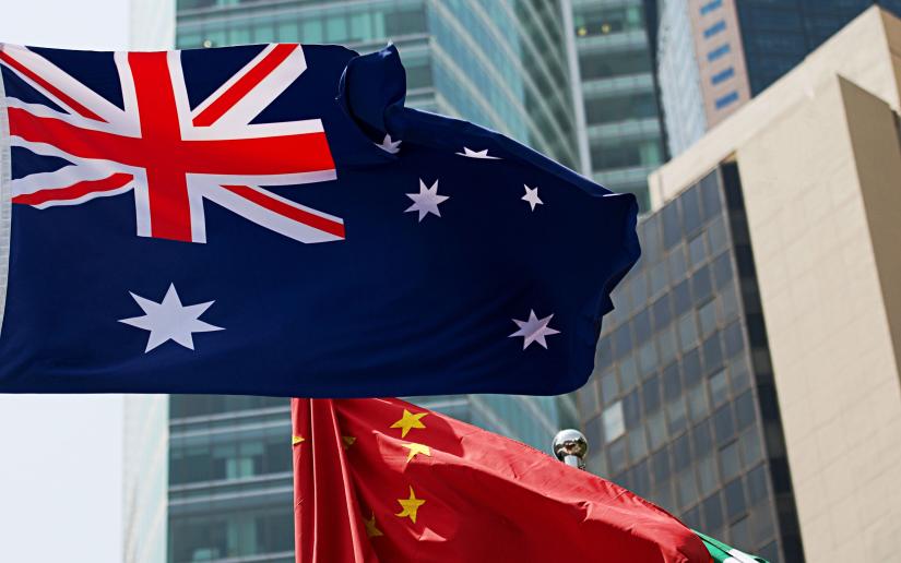 Stock picture of the Australian and Chinese flags flying with several high rise buildings in the background