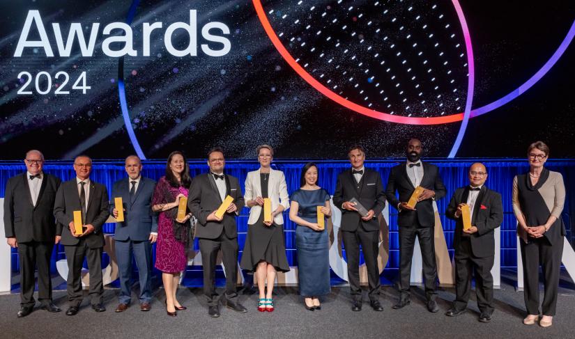 Group shot of alumni, VC and Chancellor on stage holding trophies