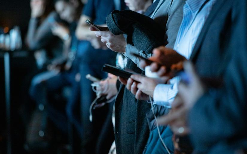 Stock picture: close up on the hands of a group of people holding smartphones