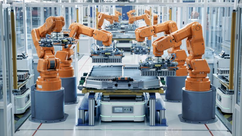 Row of robotic arms inside plant assemble batteries for automotive industry (IM Imagery / Shutterstock)