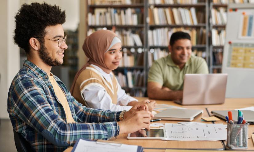 Migrant students studying together at a table. Adobe Stock By AnnaStills