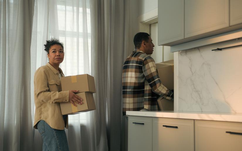 Stock picture of a man and a woman leaving a house carrying packing boxes. Picture: Yuliia/Adobe Stock