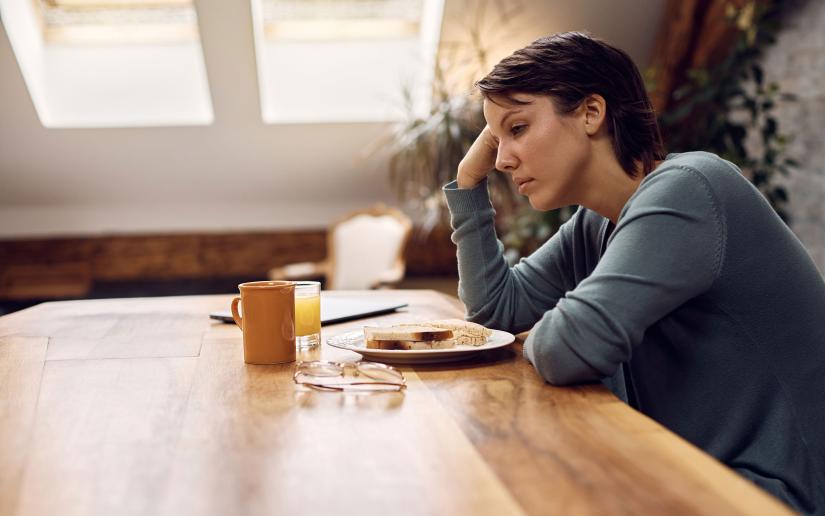 Stock picture of a thoughtful woman sitting at dining table with untouched food in front of her. Picture: Drazen/Adobe Stock.