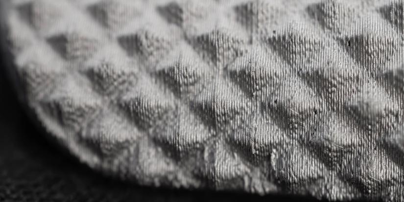 Macro view of 3D printed metal part showing clear layer lines at very fine detail