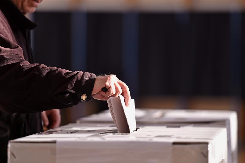 A person places a ballot in a ballot box