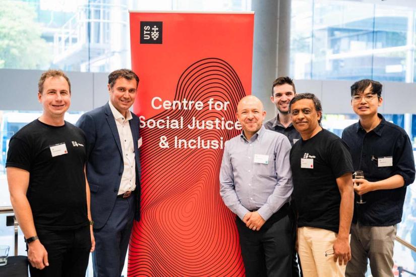 The Rapido team and Oscar Sanchez from Harris Community Centre standing in front of a UTS Centre for Social Justice & Inclusion pull up banner 