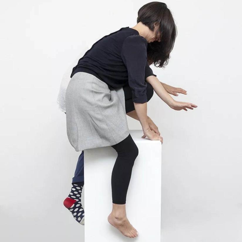 Two figures straddle a plinth. One wears polkdot socks the other is barefoot. 