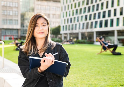Female student on Alumni Green with notebook