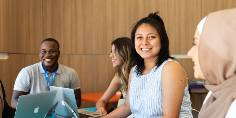 Image of students smiling using laptops