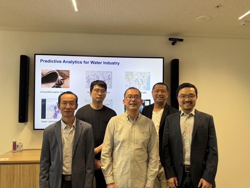 The UTS Smart Infrastructure Team stand in front of a projector in a meeting room. 