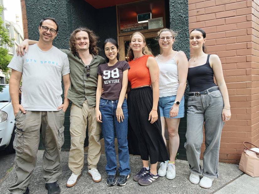 Several Biophysics individuals gathered outside a restaurant, smiling and chatting, with the restaurant's entrance visible in the background.