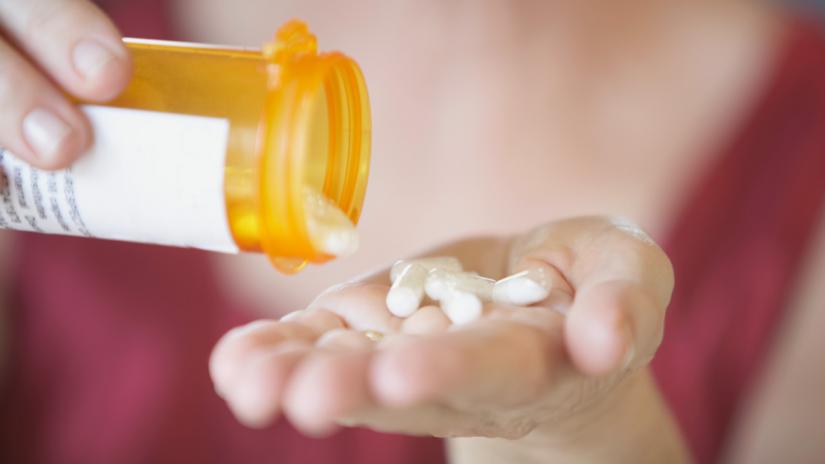 Closeup of woman pouring tablets out of a bottle and into her hand