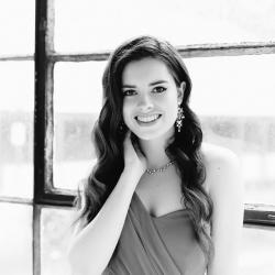 Headshot of a young woman standing in front of a window