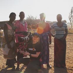 Christel with camera filming locals in Africa