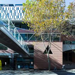 An over-street foot bridge leads into a building with a pink cement facade