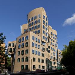 A brown brick building with multiple segments, curved walls and large square windows