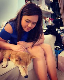 image of woman sitting on a couch with a small sandy-haired coloured dog - the woman is patting the dog's head and looking at it