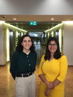 Woman in Green Shirt on the left, Woman in yellow dress on the right - standing next to each other in a hallway. 