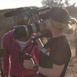 Young woman holding a video camera interviewing documentary subjects