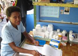 A woman sits at a desk with medicine bottles on it