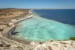 A shoreline with sand and very blue water