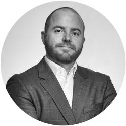 Black & White photo of a man in a suit looking at the camera in a circle