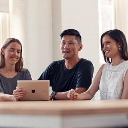 A group of three people at a table with a laptop open