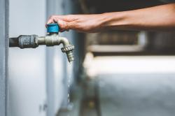 A person's hand turning off a water tap