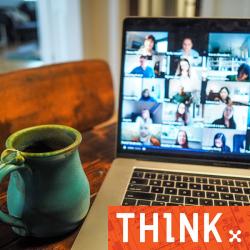 Laptop on desk showing a number of faces in a zoom meeting