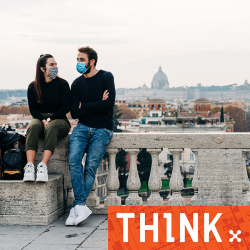 A man and a woman wearing masks sitting on a wall