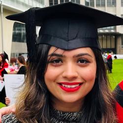 Woman wearing a mortarboard smiles into the camera.