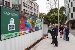 Minister Tanya Plibersek with UTS staff looking at a poster for Green Genie on campus