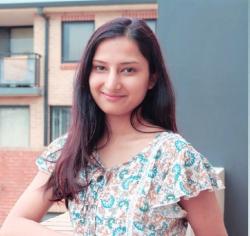 Woman smiles standing in front of apartment building.