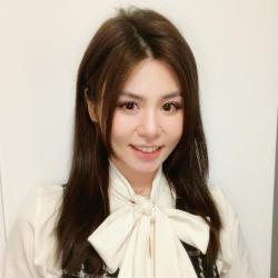 Woman in white blouse with large bow smiles.