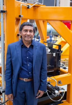 Academic Buddhima Indraratna standing in front of Rail Track Process Simulation Equipment