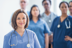 Female healthcare worker in focus and other healthcare workers behind out of focus