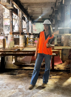 Image of a woman in a fluro-vest and hard hat at a building site