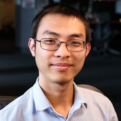 Man wearing glasses and collared shirt smiles.