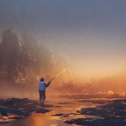 A man fishes on a quiet stretch of lake lit up gold by the light misted across the horizon