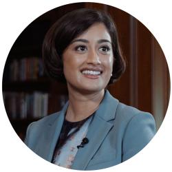 Young woman smiling and looking off camera with a short bob hairstyle in a blue suit